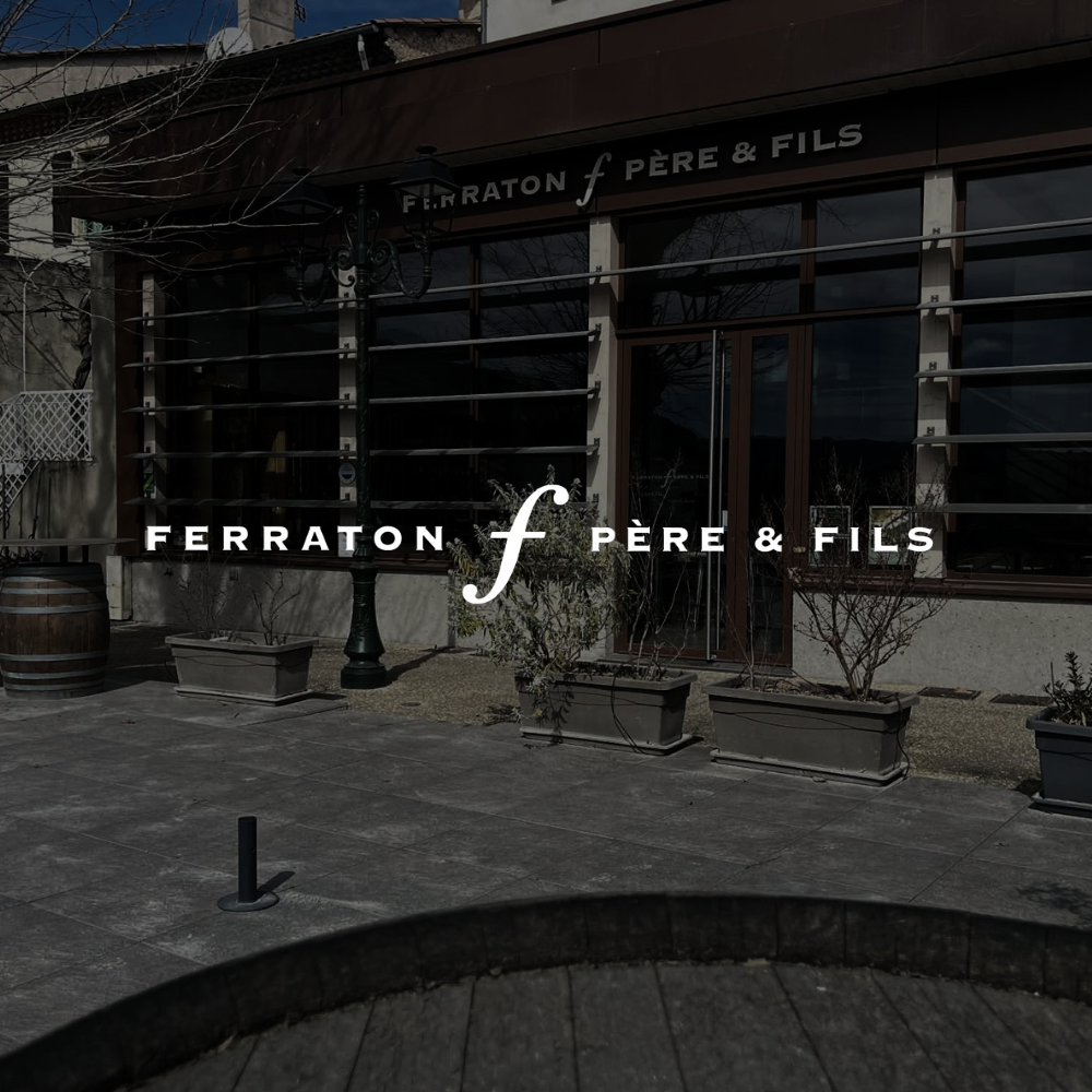 Ferraton pere & fils logo ovenpå et formørket baggrund af et af deres huse