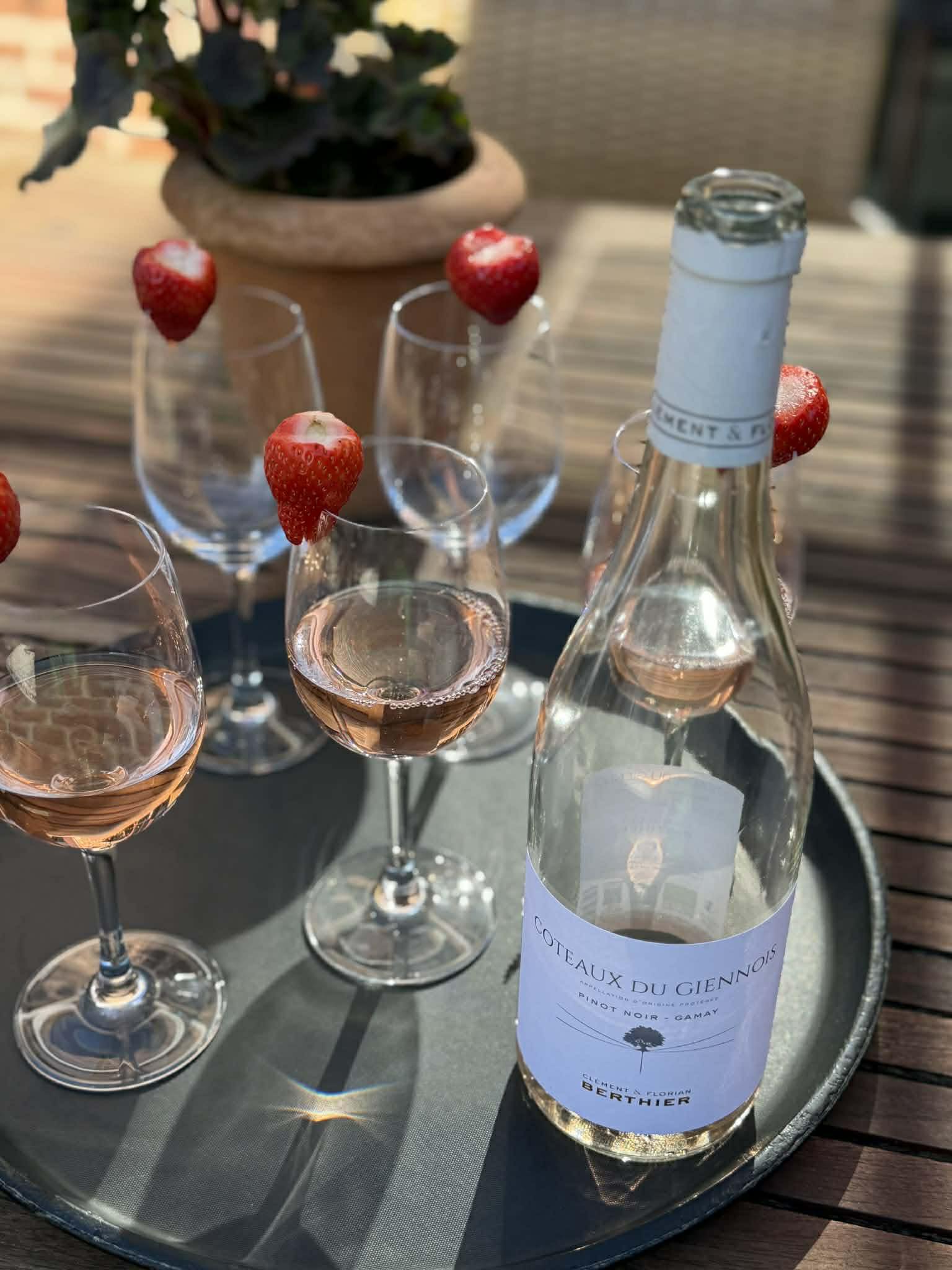 En flaske Coteaux du Giennois, sammen med nogle glas pyntet med jordbær på et træbord.