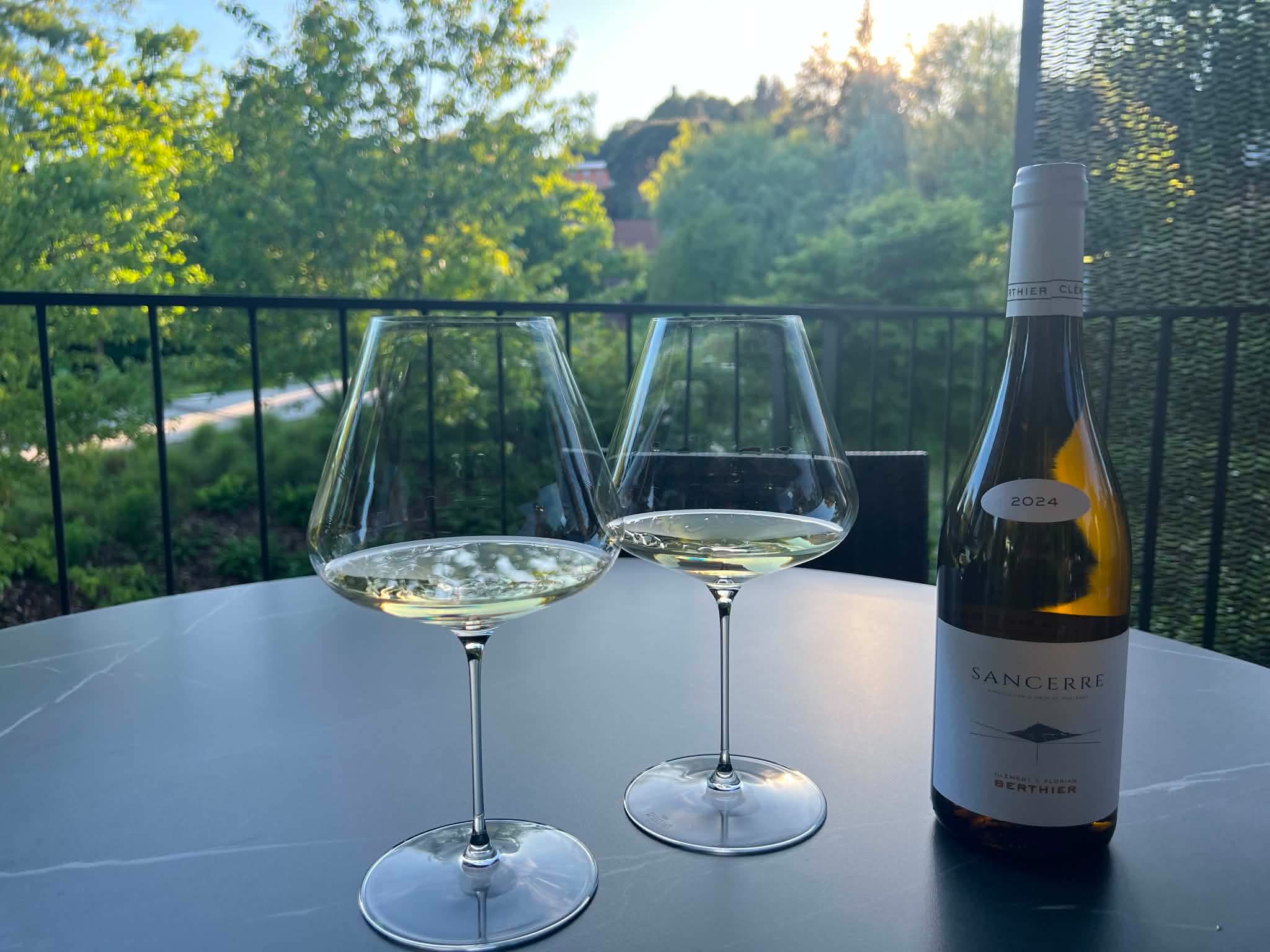En flaske vignobles berthier sancerre med 2 vinglas på et terrassebord